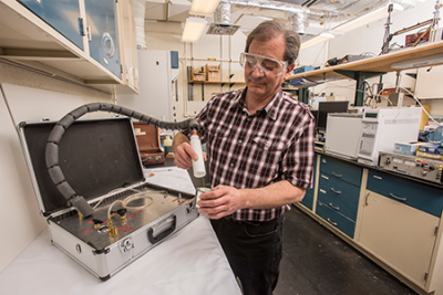 NIST chemist Tom Bruno, who invented a method for recovering trace chemicals such as environmental pollutants and forensic evidence, uses a portable version of the instrument to sample vapour inside an old paint can. The underlying technique is called PLOT-cryoadsorption. Photo courtesy NIST/ Photo by Dave Neligh
