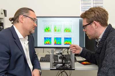Professor Dr Juergen Hauer (left) and first author Erling Thyrhaug with their instrument, and in the background, spectra taken with it. Photo: Andreas Battenberg/TUM